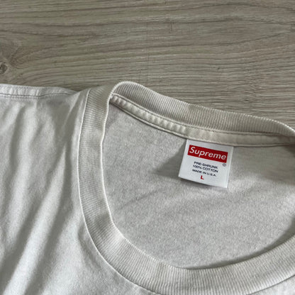 Gray t-shirt with a Supreme label on a wooden surface