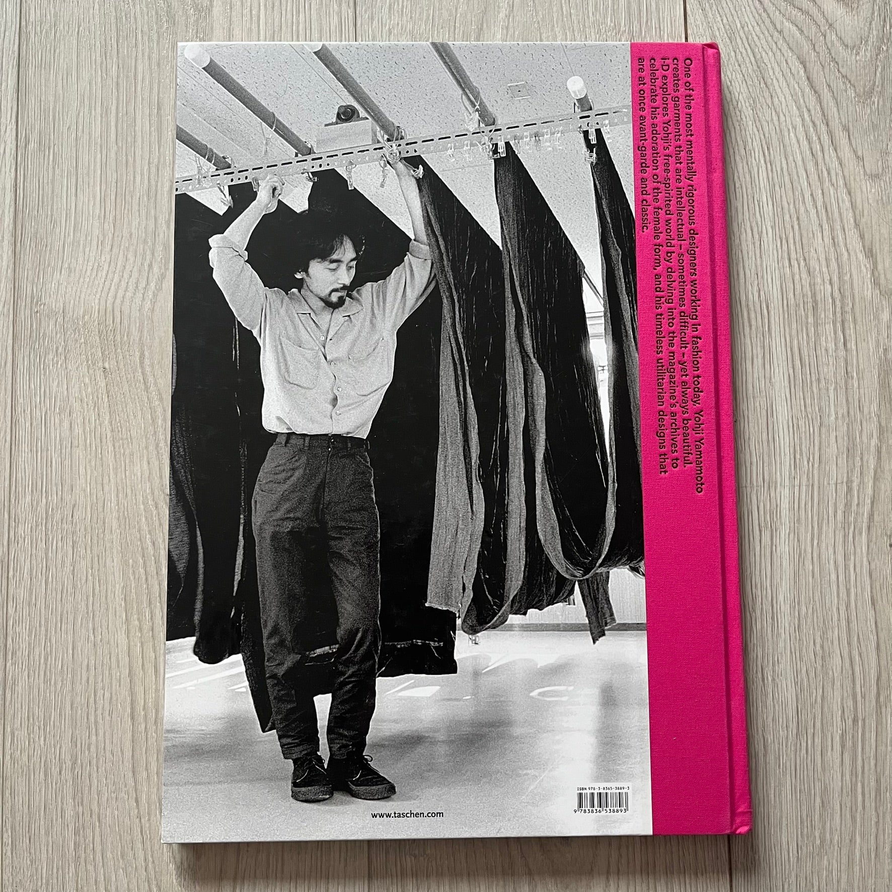 Book cover with a black and white photo of a person hanging clothes on a rack, pink spine.