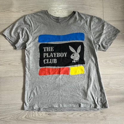 Gray t-shirt with Playboy Club logo on a wooden surface