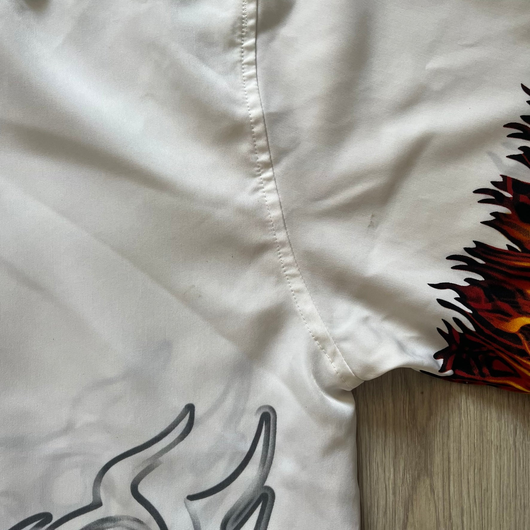 Close-up of a white shirt with black and brown designs on a wooden surface