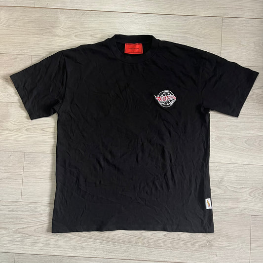Black t-shirt with a logo on a wooden floor