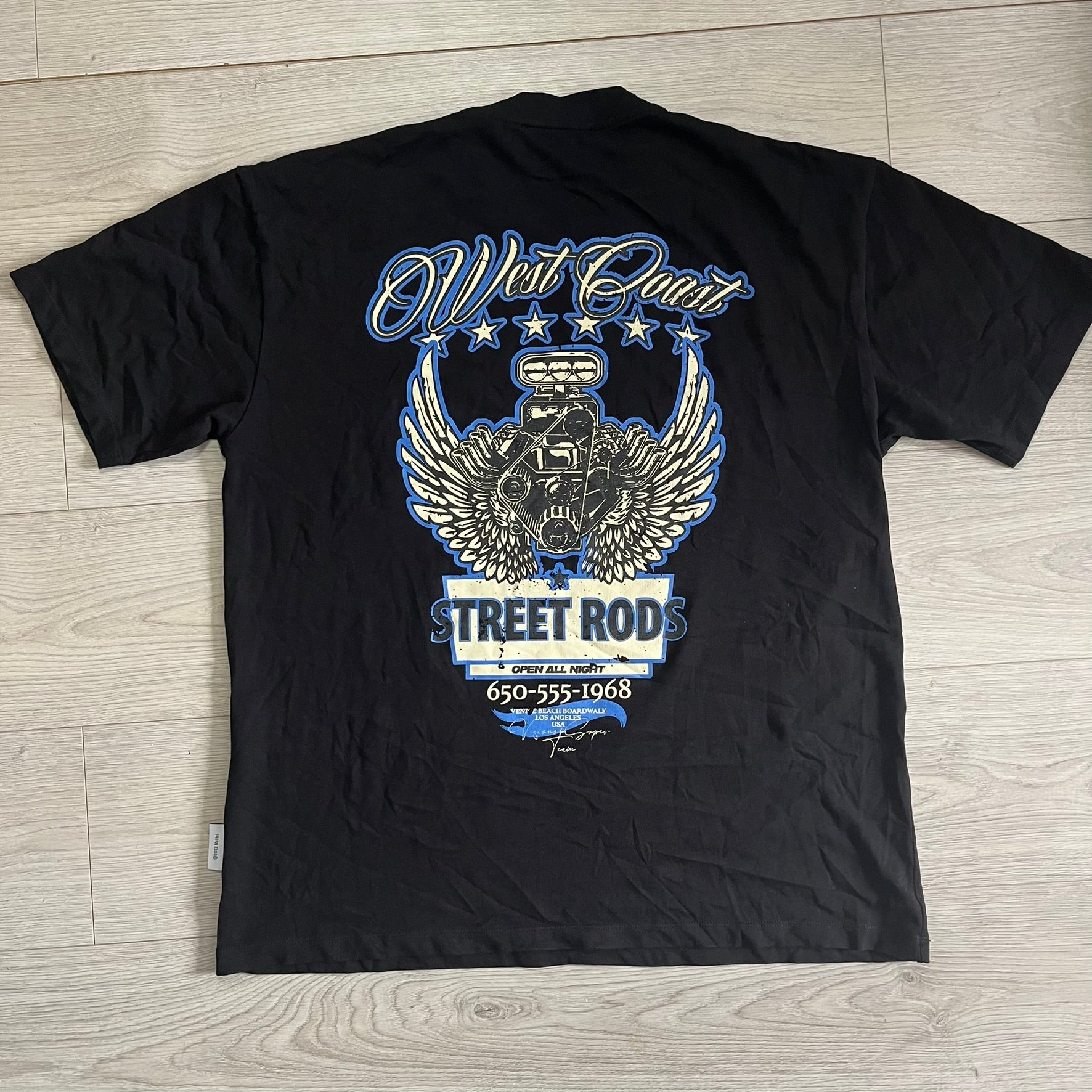 Black t-shirt with blue and white graphic design on a wooden surface