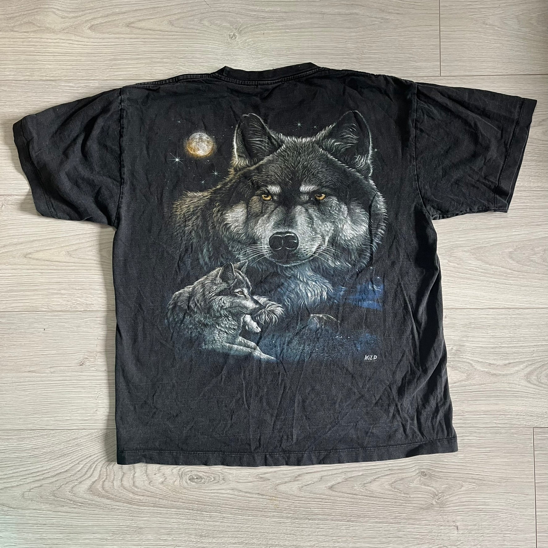 Black t-shirt with a wolf graphic on a wooden surface